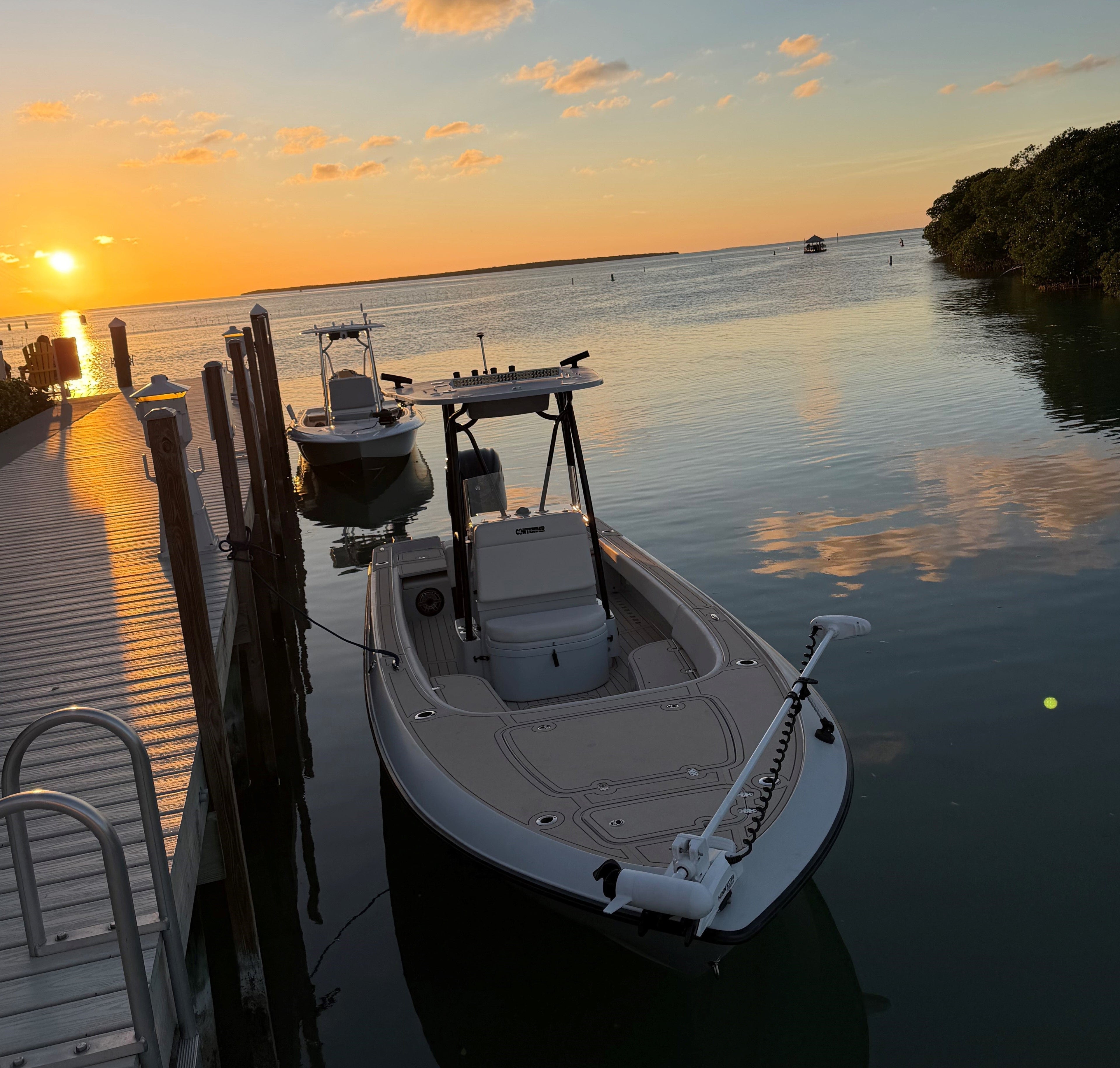 Boat docked at a pier during sunset with calm water and sky.